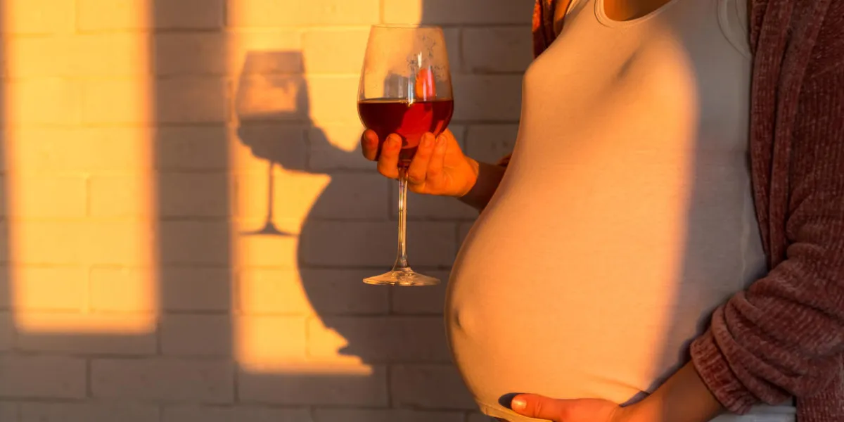 unrecognized pregnant woman with glass of red wine in hand
