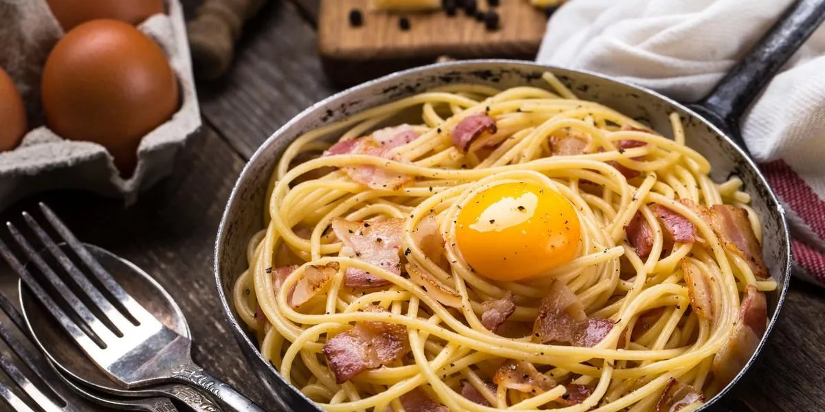 pasta with bacon, egg and cheese on a wooden table
