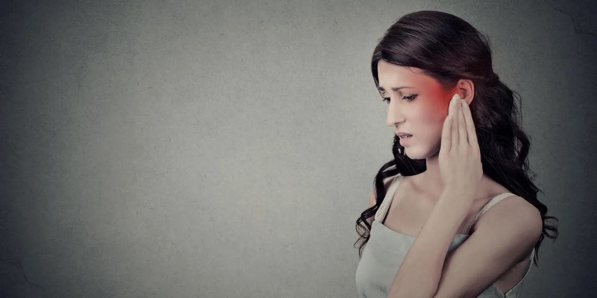 tinnitus closeup up side profile sick female having ear pain touching her painful head temple colored in red isolated on gray wall background with blank copy space tinnitus closeup up side profile sick female having ear pain touching her painful head temple colored in red isolated on gray wall background with blank copy space