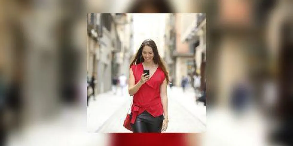 vue de face d'une femme heureuse de la mode à pied et en utilisant un téléphone intelligent sur une rue de la ville vue de face d'une femme heureuse de la mode à pied et en utilisant un téléphone intelligent sur une rue de la ville