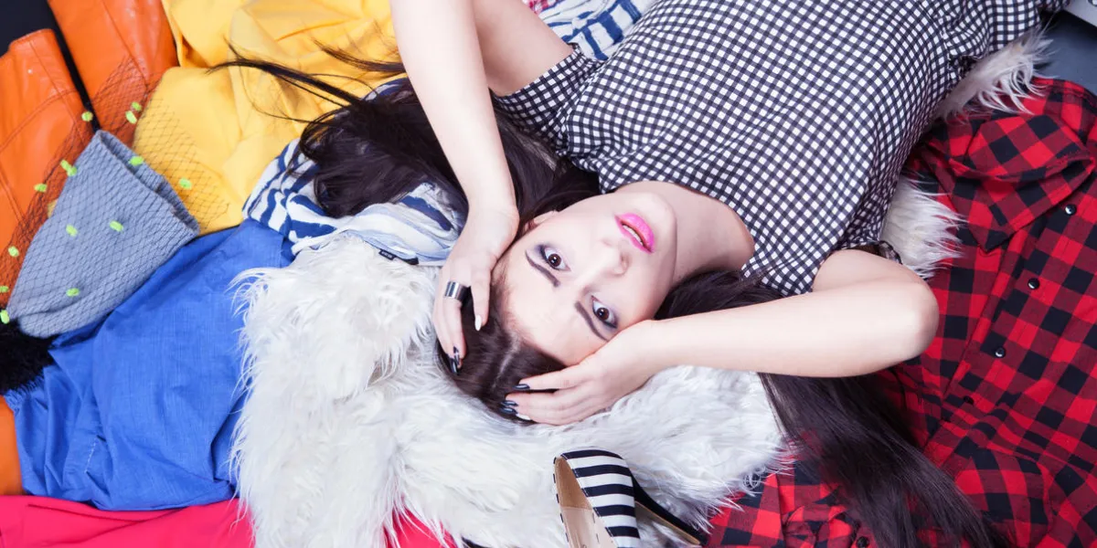nothing to wear concept, young attractive stressed woman lying down on a pile of clothes nothing to wear concept, young attractive stressed woman lying down on a pile of clothes