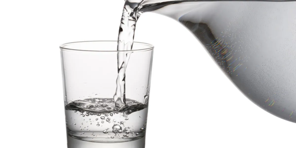 verser de l'eau dans le verre d'une carafe, sur fond blanc