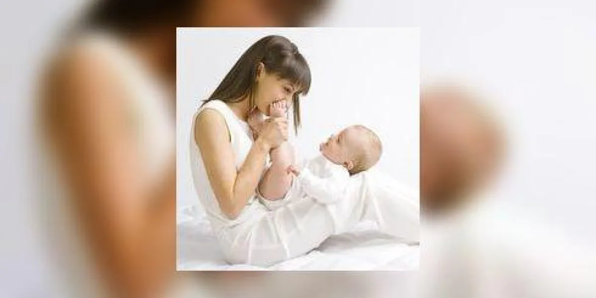 jeune maman avec bébé garçon assis sur un chiffon blanc et s'amuser tout le corps, vue de côté