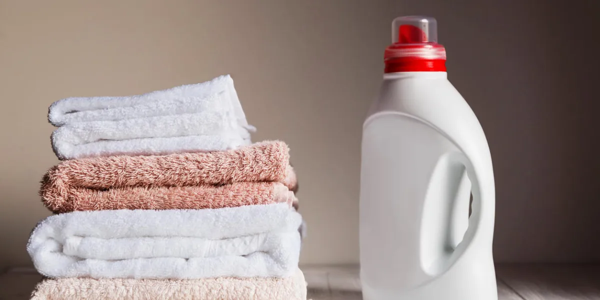 stack of several coloured and white towels and bottle with cosmetic product