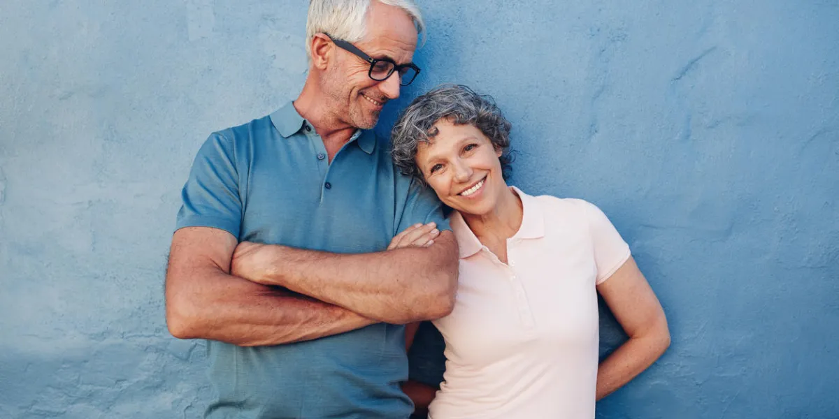 portrait de la belle femme mature debout avec son mari sur fond bleu amour couple mature debout ensemble contre un mur bleu