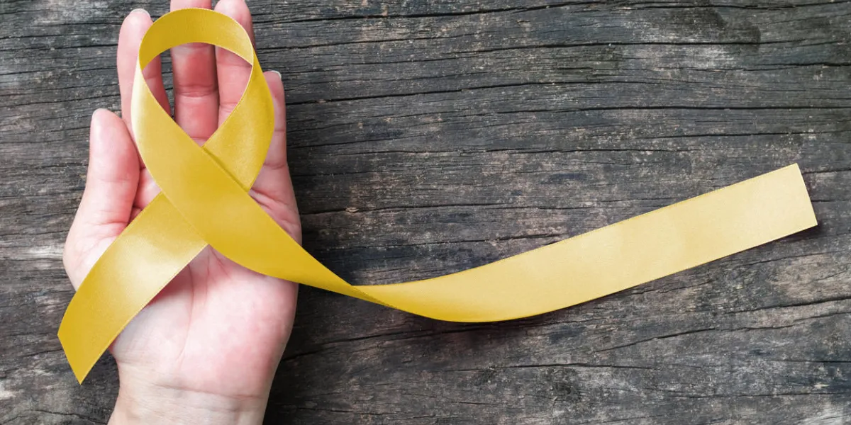 yellow ribbon symbolic color for sarcoma bone cancer, spina bifida awareness month and suicide prevention on helping hand (isolated with clipping path)