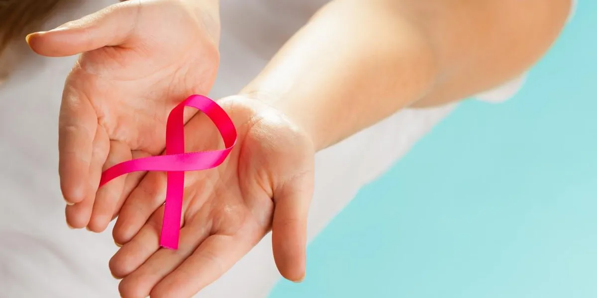 healthcare and medicine concept - woman hands holding pink breast cancer awareness ribbon on blue healthcare and medicine concept - woman hands holding pink breast cancer awareness ribbon on blue