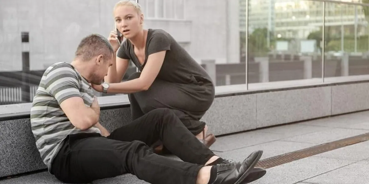 woman calling ambulance for man suffering from heart attack outdoors woman calling ambulance for man suffering from heart attack outdoors
