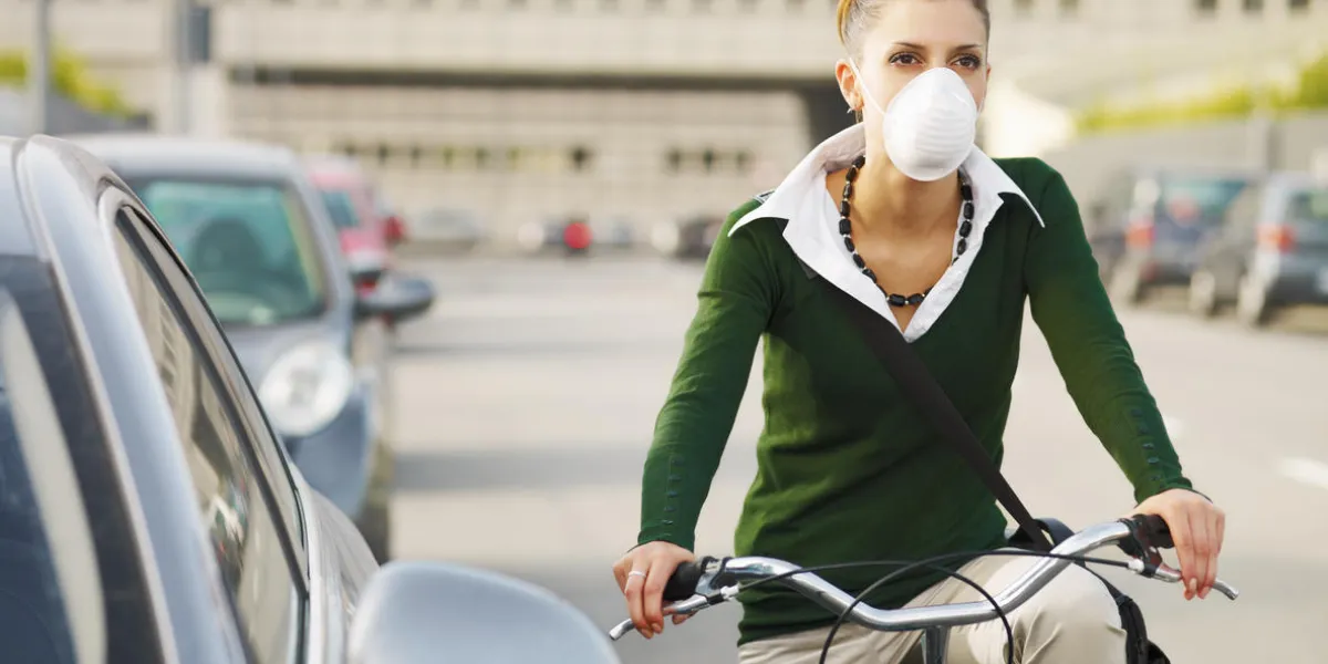 woman with dust mask commuting on bicycle woman with dust mask commuting on bicycle