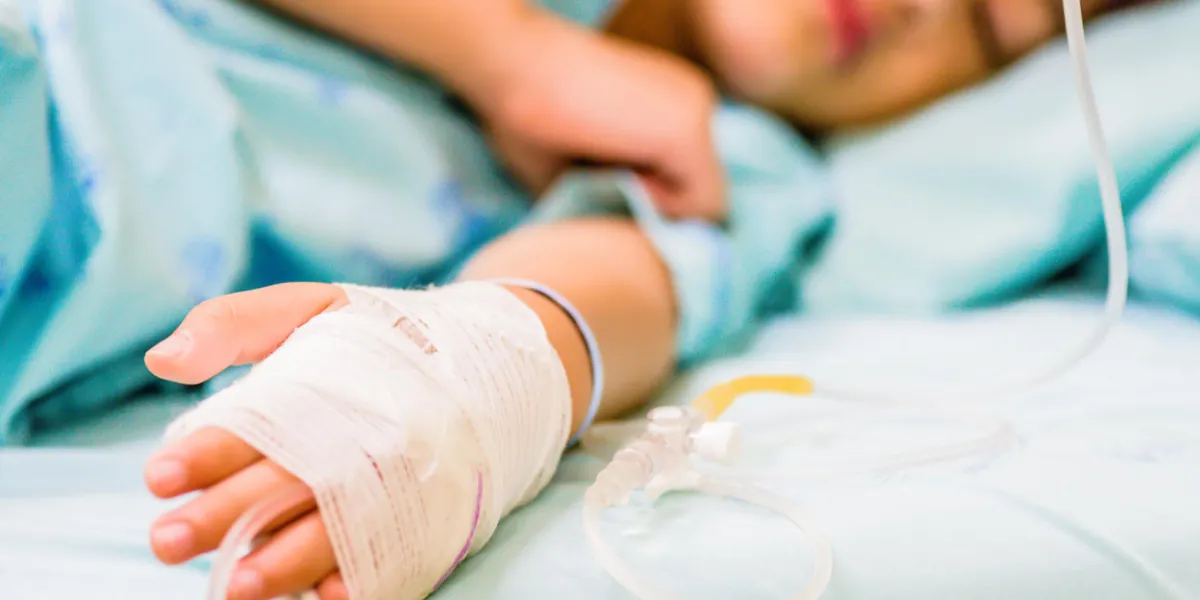 closeup kid hand sleeps on a bed in hospital with saline intravenous