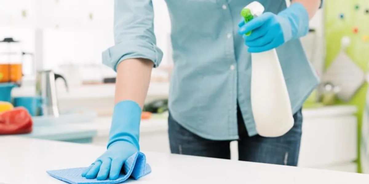 woman cleaning and polishing the kitchen worktop with a spray detergent, housekeeping and hygiene concept