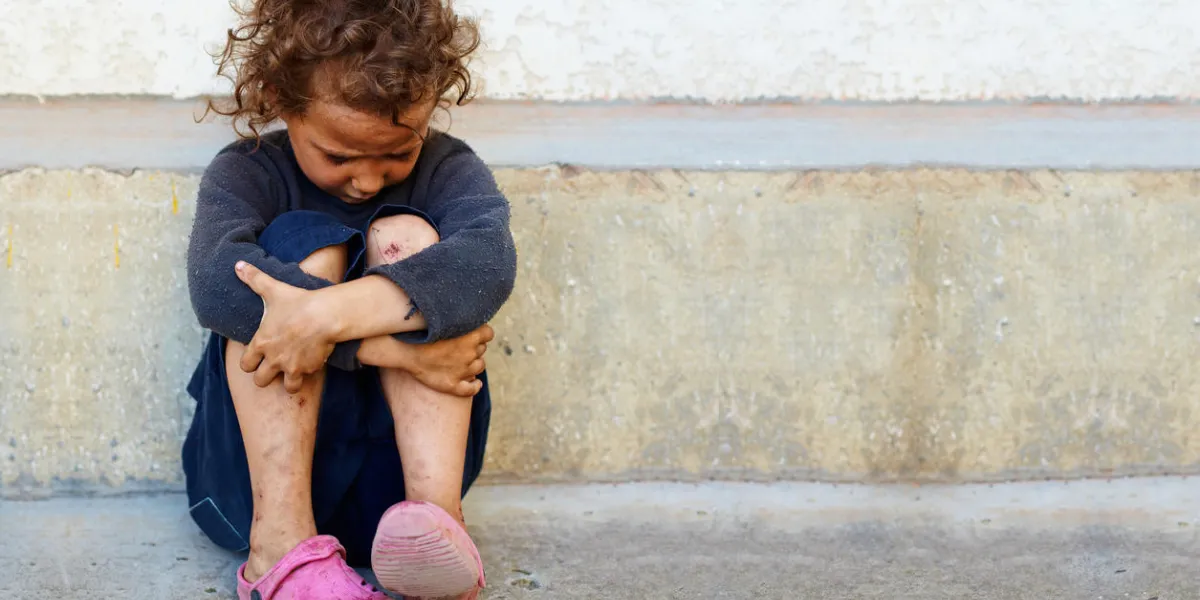 pauvre, triste petite fille enfant assise contre le mur de béton pauvre, triste petite fille enfant assise contre le mur de béton