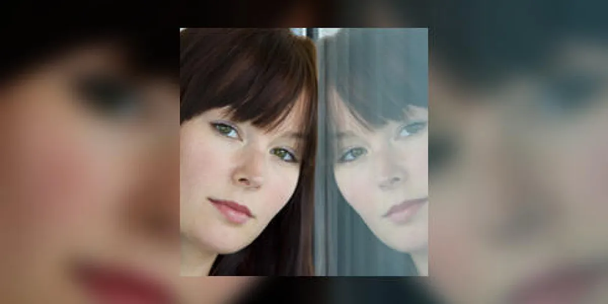 une belle jeune femme regarde avec nostalgie dans une fenêtre où son reflet se retourne vers elle