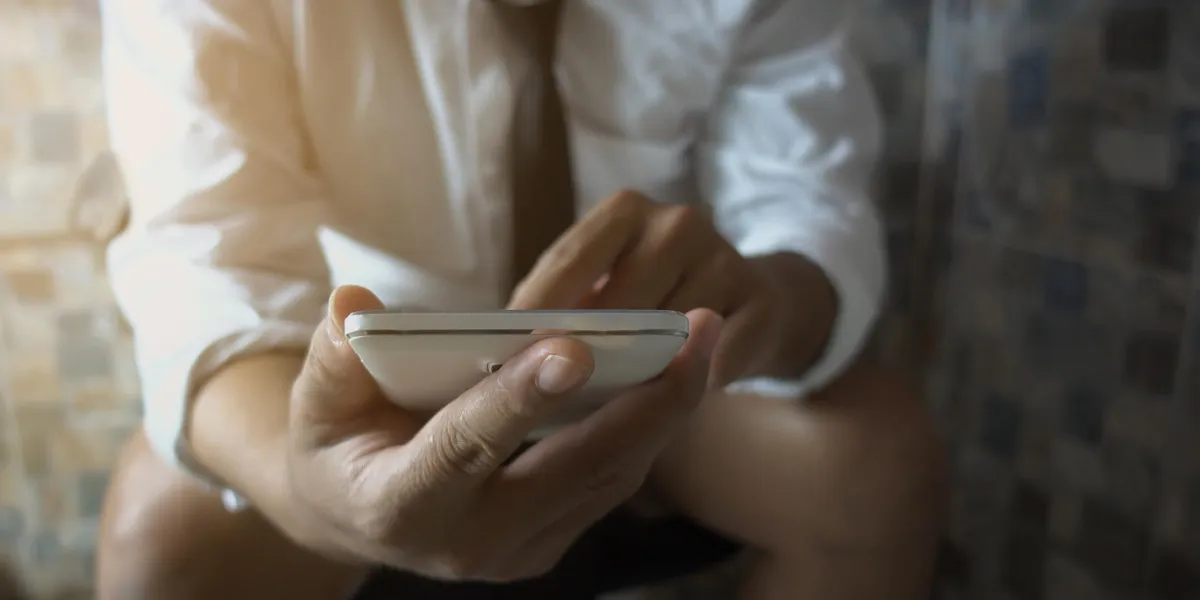 selective focus of business man playing a game of smart phones in the toilet