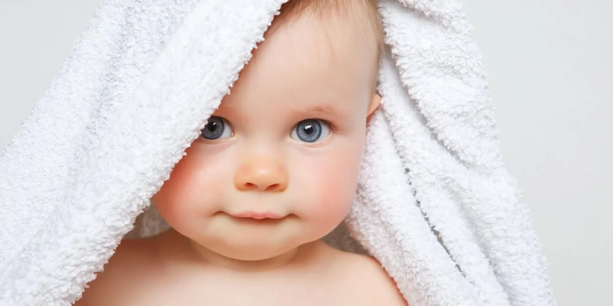 petit bébé souriant sous une serviette blanche petit bébé souriant sous une serviette blanche
