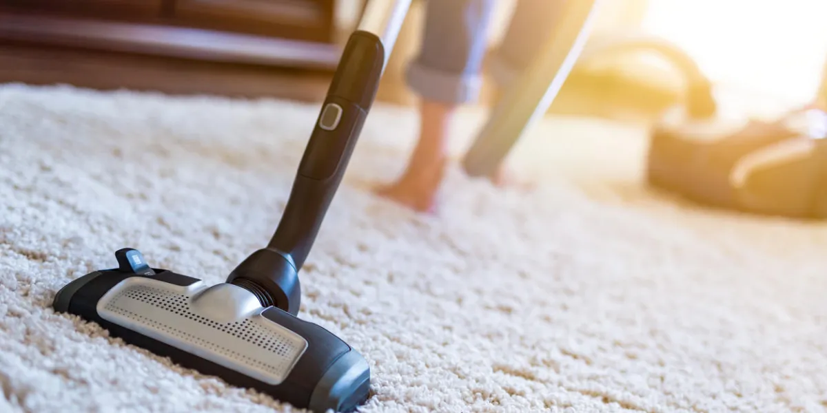 young woman using a vacuum cleaner while cleaning carpet in the house young woman using a vacuum cleaner while cleaning carpet in the house