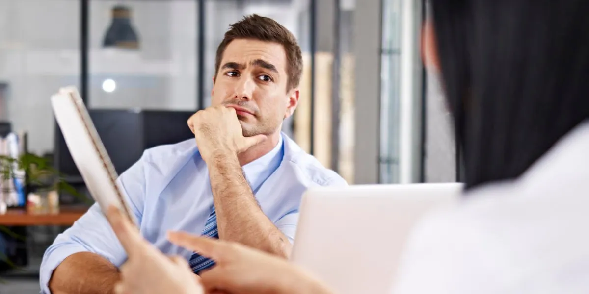 un interviewer caucasien mâle regardant sceptique tout en écoutant une femme interviewée asiatique un interviewer caucasien mâle regardant sceptique tout en écoutant une femme interviewée asiatique