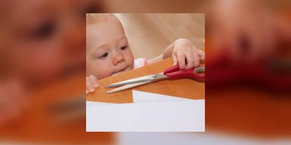 un bébé qui tend une paire de ciseaux sur une table