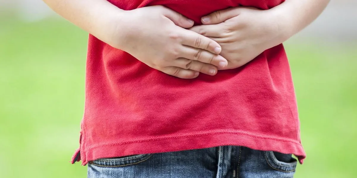 child with stomach ache, little boy holding hands on his belly