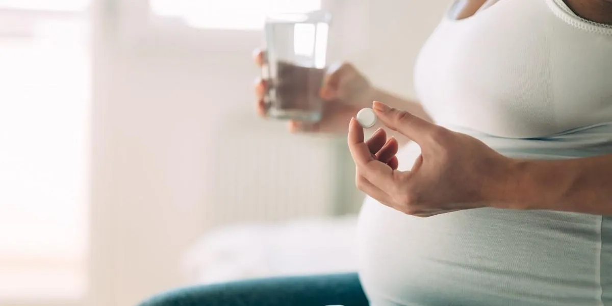 picture of pregnant woman taking medication pills at home