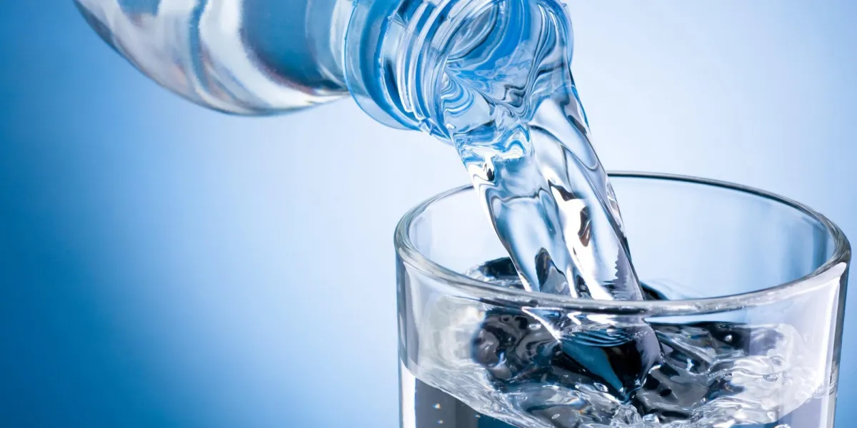 verser l'eau de la bouteille dans le verre sur fond bleu