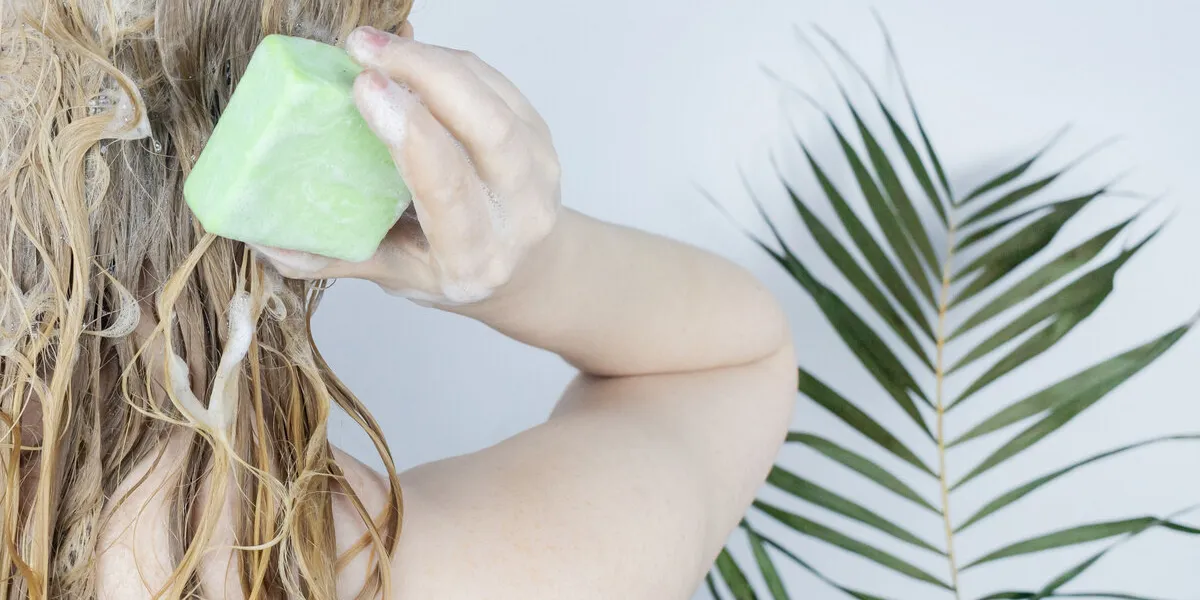 solid hair shampoo close-up of a blonde girl in the bathroom, which lathers her hair with dry shampoo lots of foam and peek effect