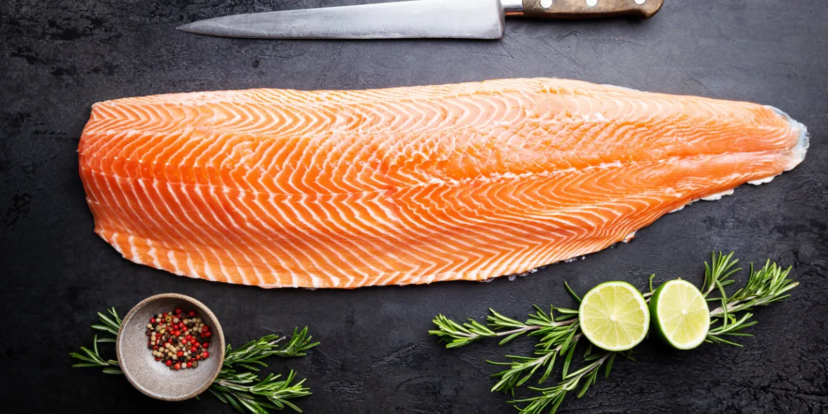 fresh raw salmon or trout sea fish fillet with spices and herbs on black background, top view