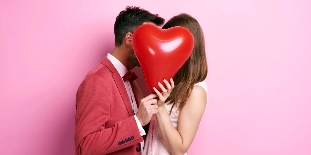 affectionate couple covering face with balloon and kissing affectionate couple covering face with balloon and kissing