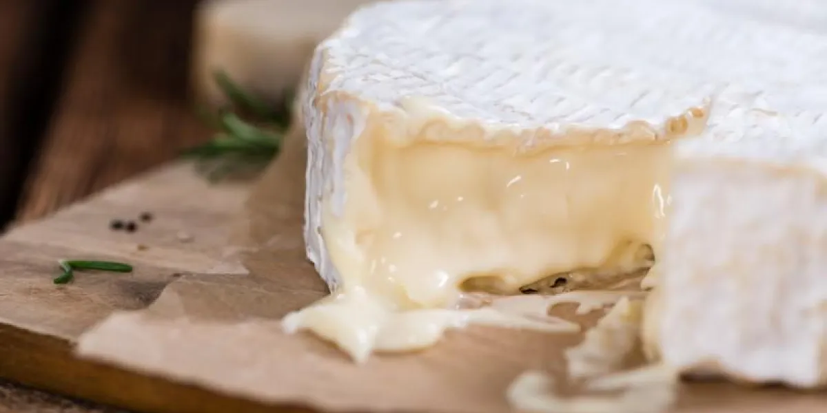 portion de camembert crémeux (gros plan détaillé) sur fond en bois rustique
