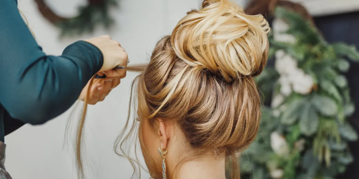 hairdresser makes complex and beautiful hairstyle upper bun suitable for evening and wedding style