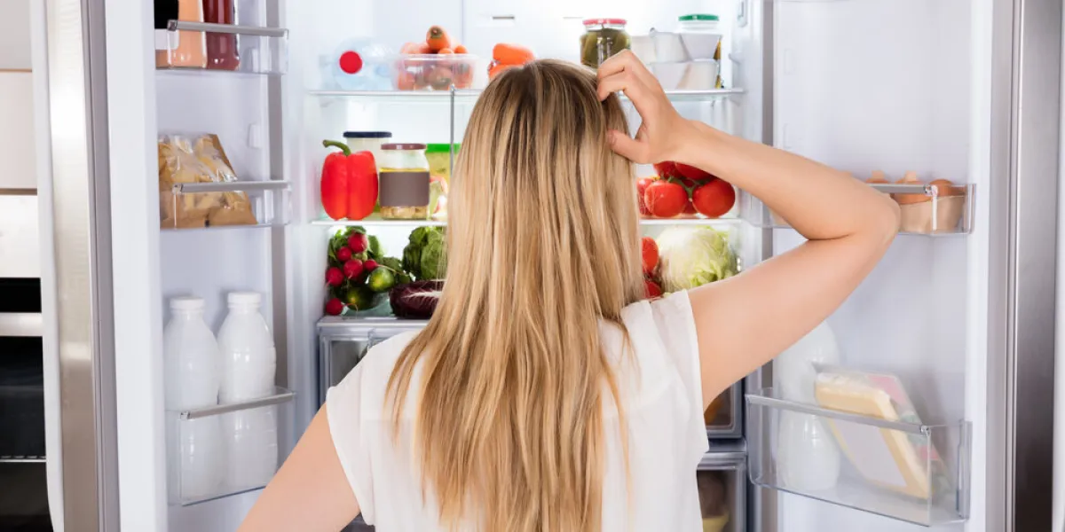 rear view of young woman looking in fridge at kitchen