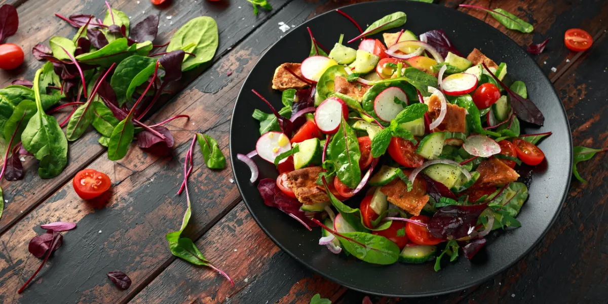 traditional fattoush salad on a plate with pita croutons, cucumber, tomato, red onion, vegetables mix and herbs