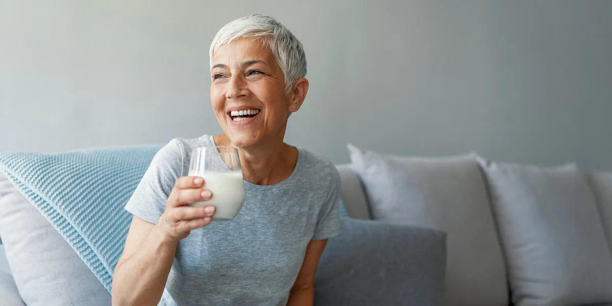 senior woman's hands holding a glass of milk happy senior woman having fun while drinking milk at home senior woman drinking a glass of milk to maintain her wellbeing senior woman's hands holding a glass of milk happy senior woman having fun while drinking milk at home senior woman drinking a glass of milk to maintain her wellbeing