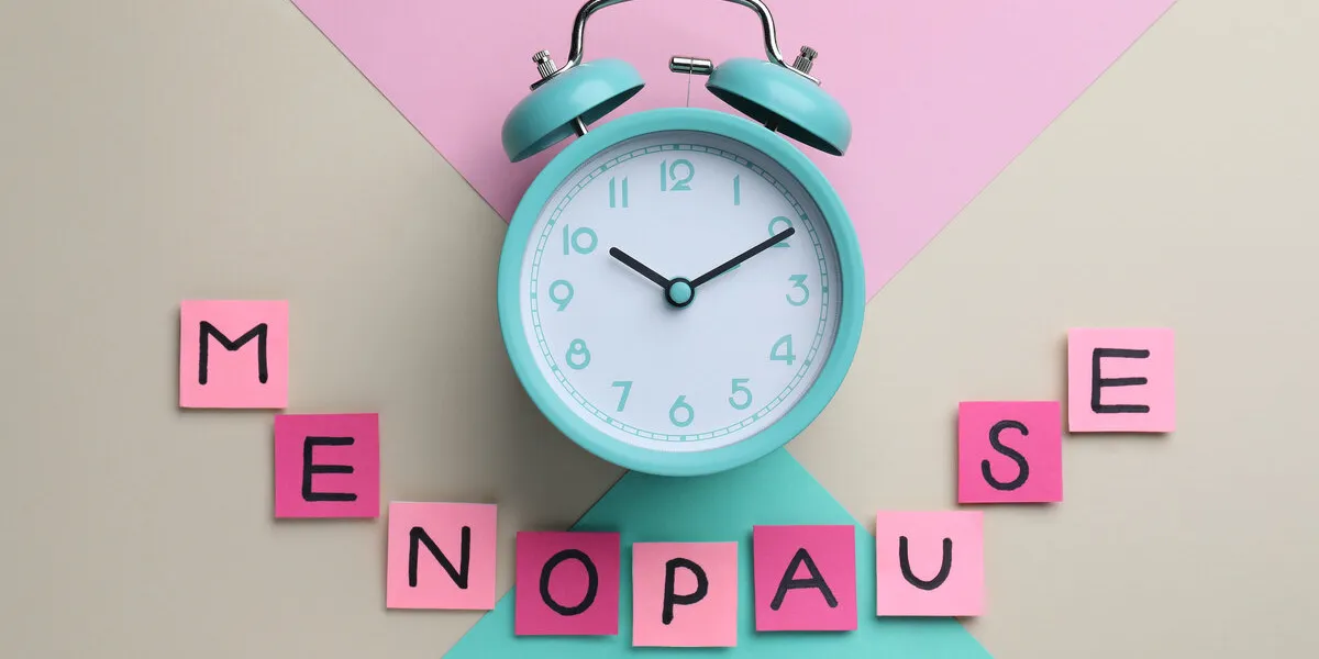 pink paper notes with word menopause and alarm clock on color background, flat lay