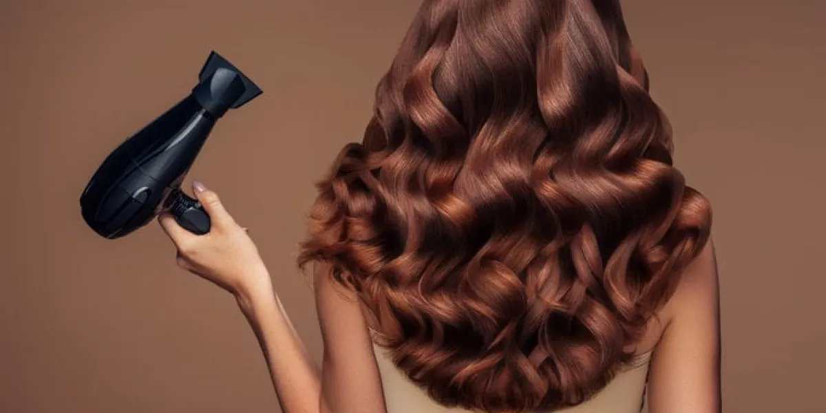 girl with a beautiful hairstyle holding a hairdryer