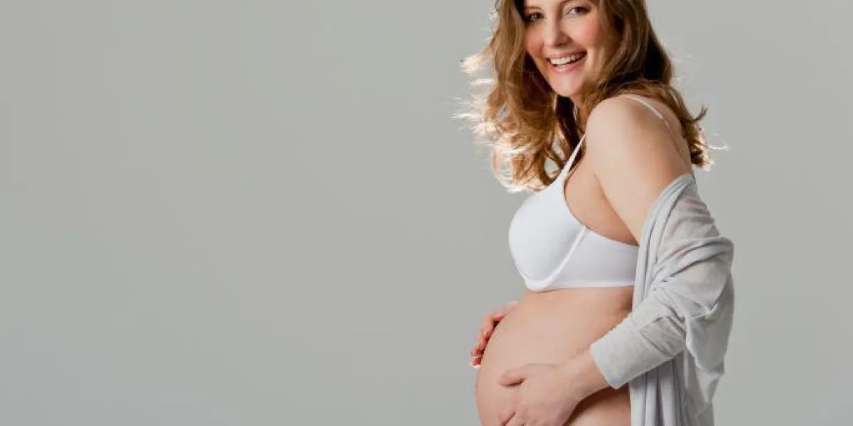 portrait de jeune femme enceinte tenant le ventre, souriant