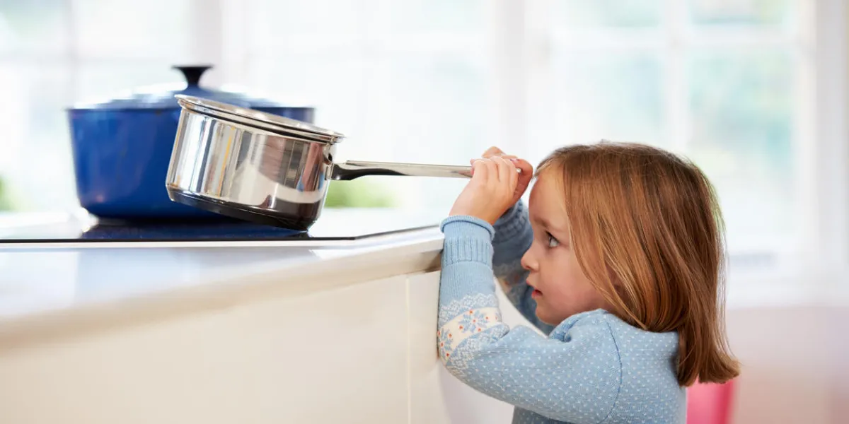 jeune fille risquer accident avec pan dans la cuisine brillamment éclairée jeune fille risquer accident avec pan dans la cuisine brillamment éclairée