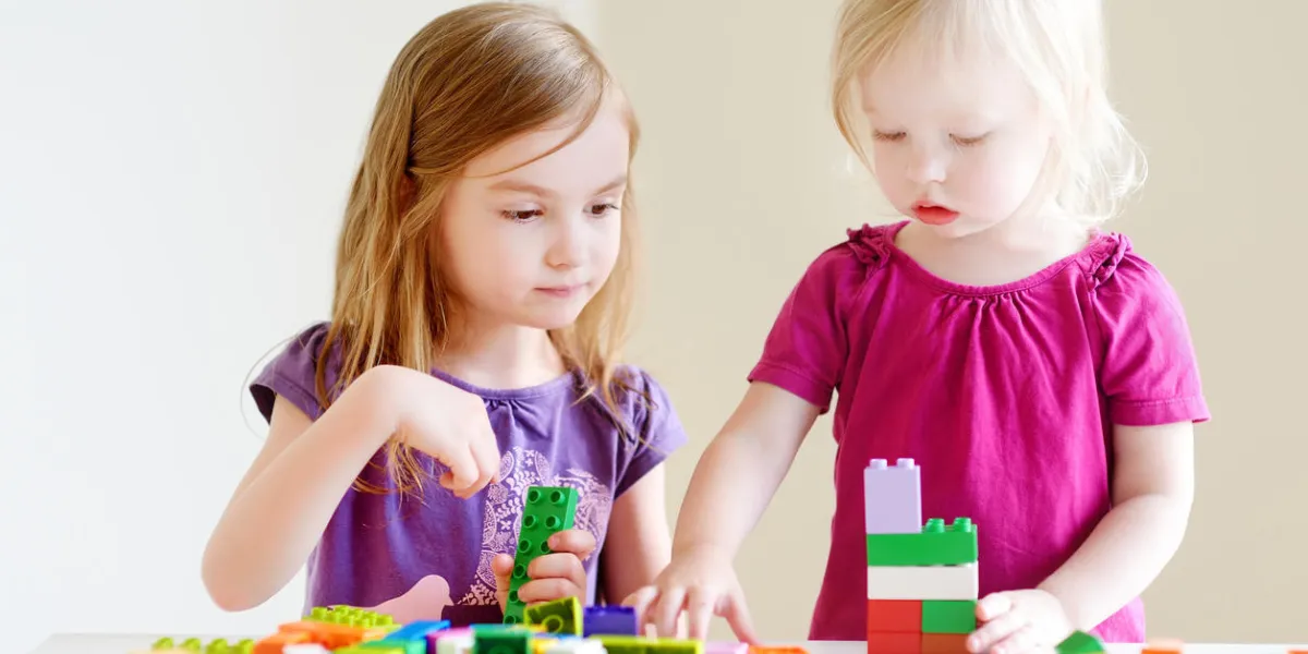 deux petites soeurs mignonnes jouant avec des blocs de plastique colorés à la maison