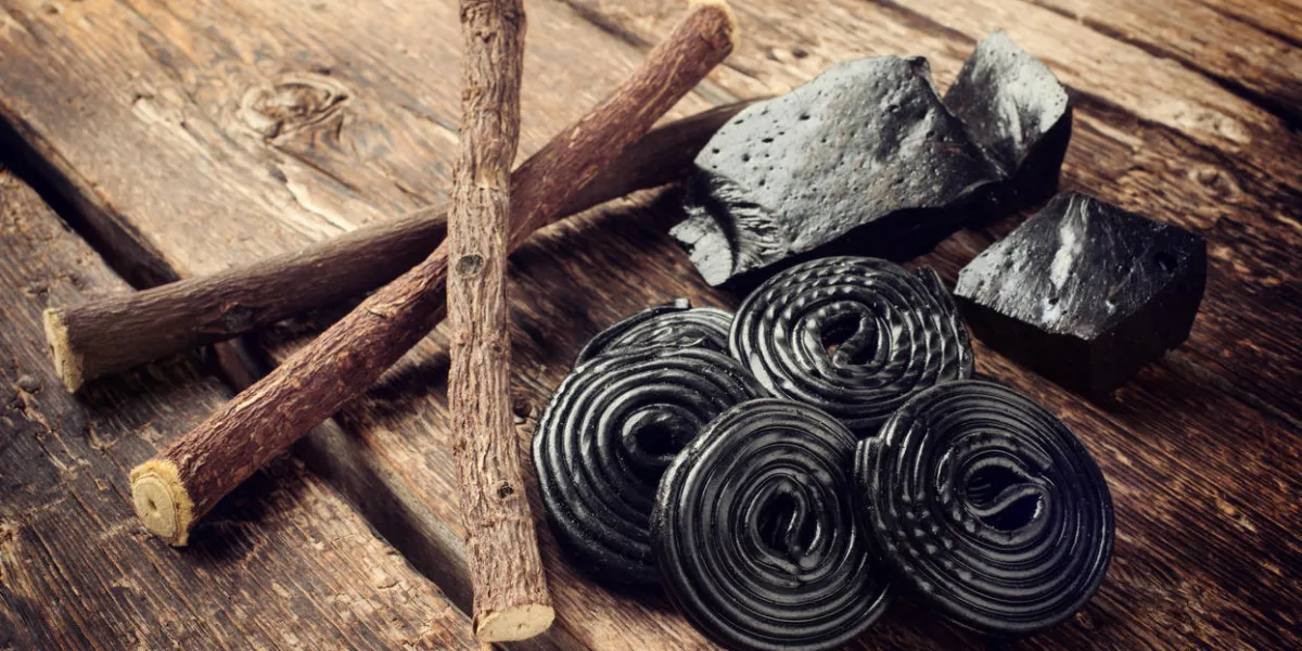 étapes de production de réglisse, racines, blocs purs et bonbons sur la table en bois