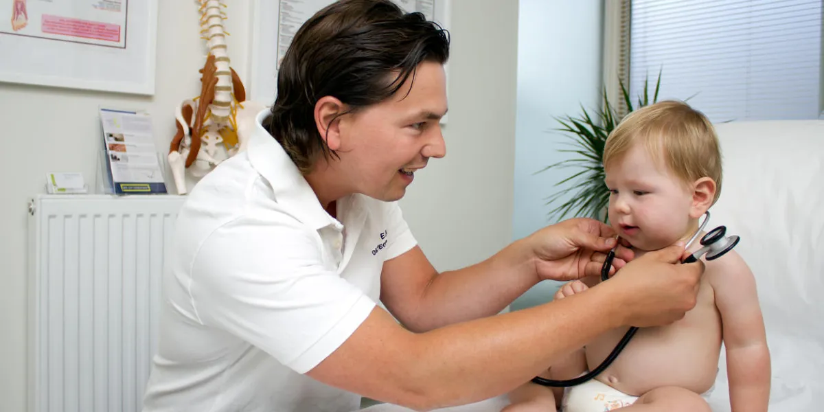 docteur ostéopathe jouant avec bébé et stéthoscope
