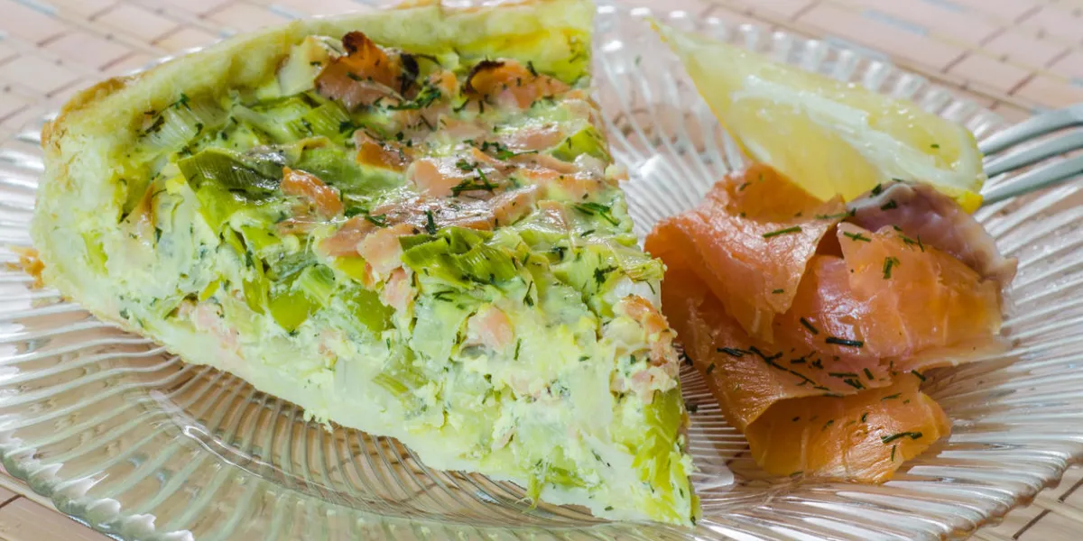 portion of salmon and leek quiche with smoked salmon and lemon