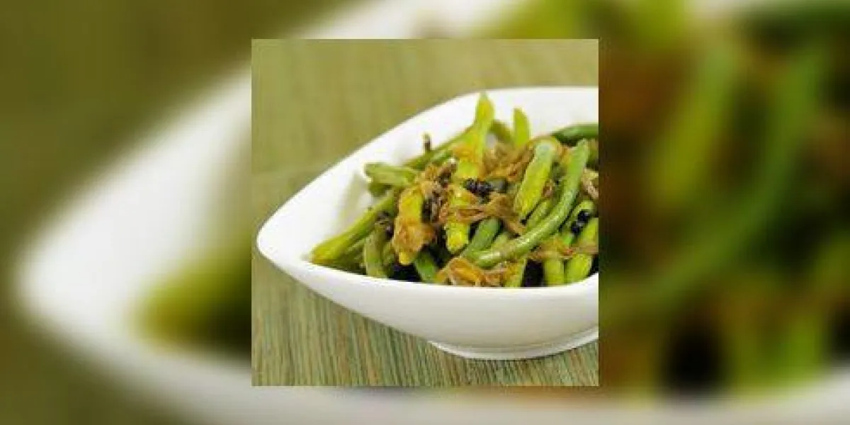 un plat de légumes composé de haricots verts, d'oignons et d'épices au curry, tourné dans une direction légèrement inclinée
