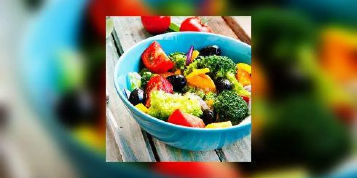 salade tiède avec du brocoli, des tomates, des oignons rouges et des olives dans un bol bleu