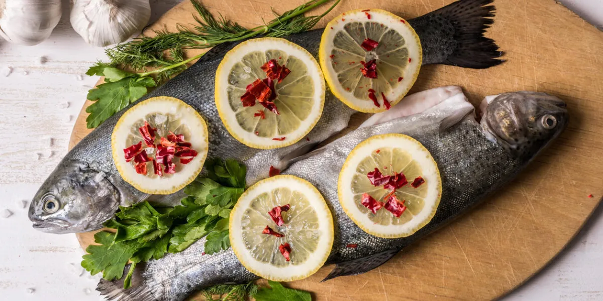 plat de poisson cuisson avec divers ingrédients truite arc-en-ciel cru avec le citron, l'ail, les herbes et les épices sur une planche à découper, vue de dessus des aliments sains ou un concept de nutrition diététique