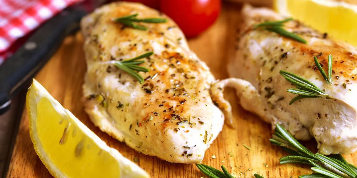 poitrine de poulet cuite au romarin sur une planche à découper poitrine de poulet cuite au romarin sur une planche à découper