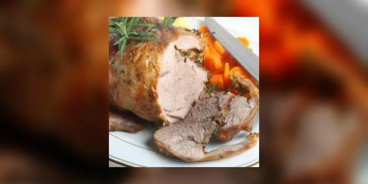 une assiette de service avec un joint de pommes de terre rôties et d'agneau rôties désossées et des carottes bouillies, garnie de brins de romarin