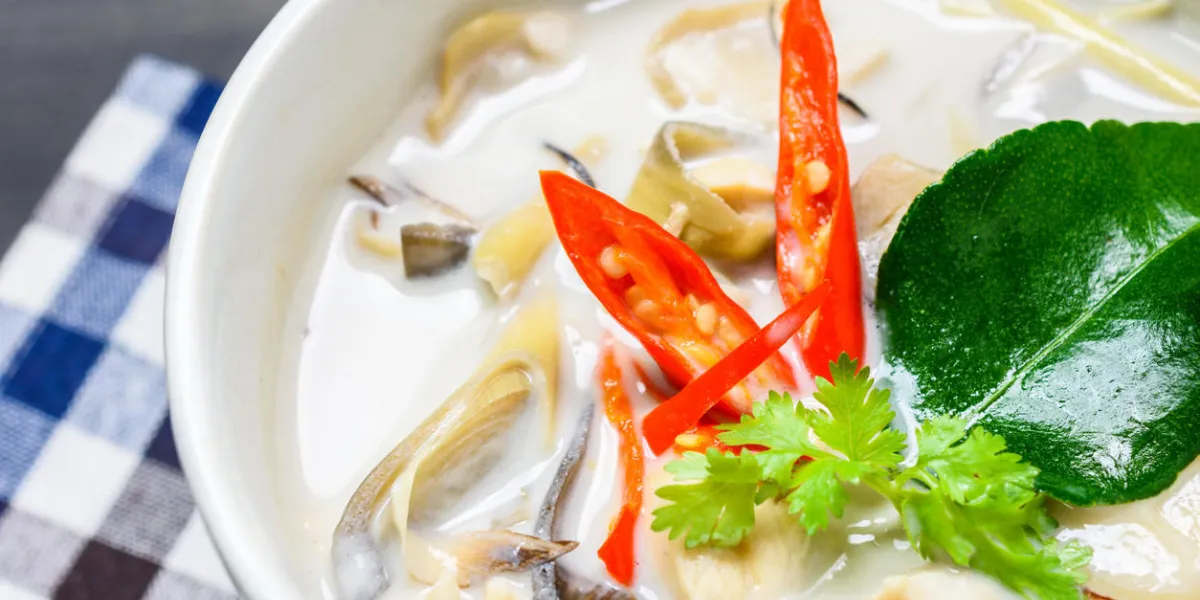 bouchent avec de la soupe de lait de coco avec du poulet ou de la soupe de noix de coco thaïe de poulet (tom kha gai) sur bois avec nappe, vue de dessus de table, nourriture locale thaïlandaise