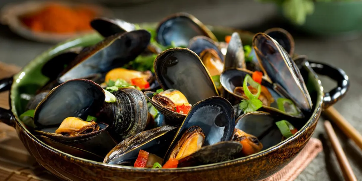 délicieuses moules cuites à la vapeur de style asiatique avec poivron rouge, oignon vert et coriandre dans un bouillon de noix de coco