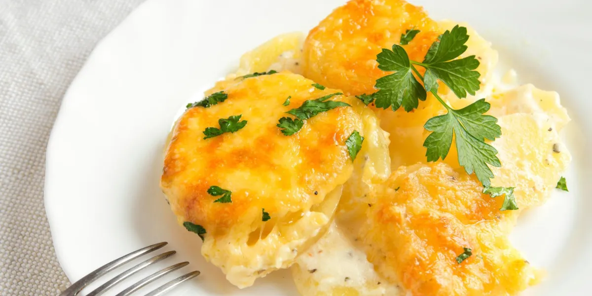 gratin de pommes de terre à la crème, au fromage et au persil sur une assiette blanche