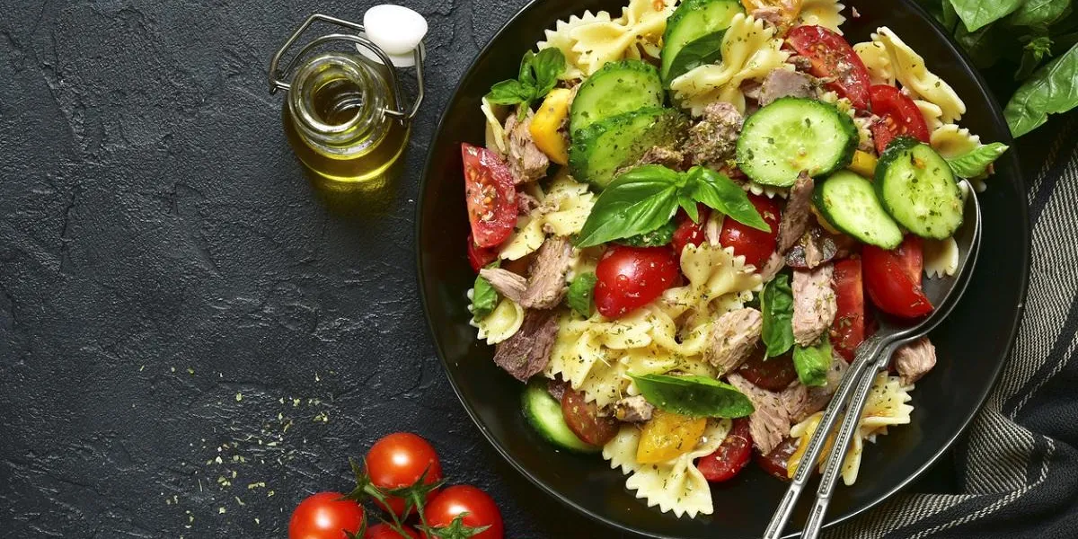 tuna salad with pasta and vegetables in a black bowl on a dark slate,stone or concrete backgroundtop view tuna salad with pasta and vegetables in a black bowl on a dark slate,stone or concrete backgroundtop view